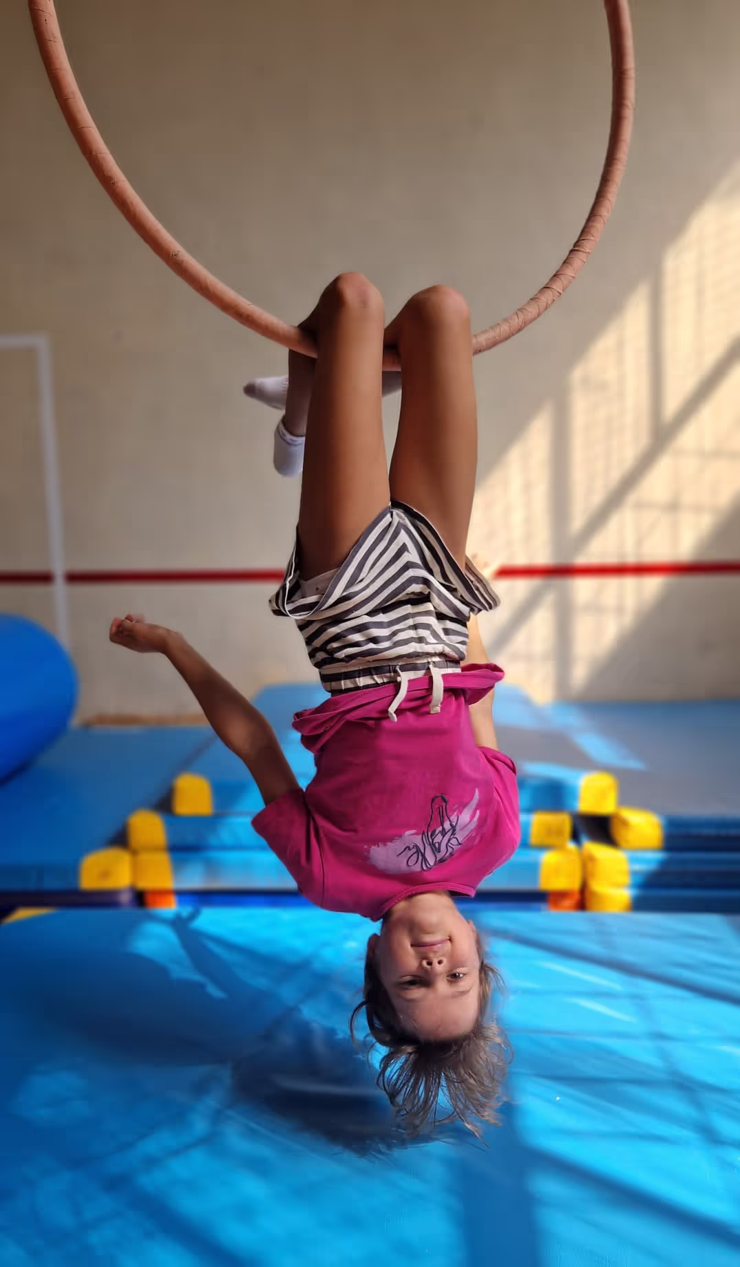 Dziewczynka na kółku (aerial hoop) wisi do góry nogami na zajęciach akrobatycznych Akademia Everest.